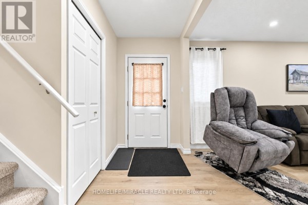 Living room with a sofa, reclining chair, television, and stairs leading down. - 365 Blue Forest Drive, London North