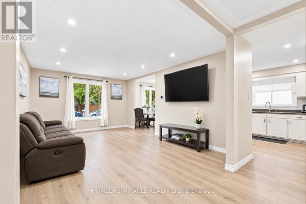 Living room with laminate flooring, furniture, television, and stairs leading to another level. - 365 Blue Forest Drive, London North