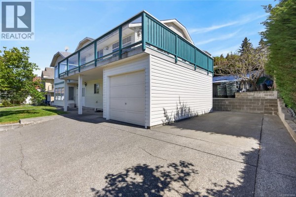 Side view of a white house with a garage and a covered area under the deck. - 365 Panorama Cres, Courtenay