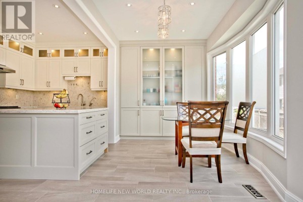 Kitchen area with a small dining table, chairs, and large windows overlooking the backyard. - 365 Tonelli Lane, Milton