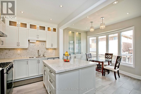 Bright and airy kitchen and dining area with white cabinets, a large island, and dining table by bay windows. - 365 Tonelli Lane, Milton