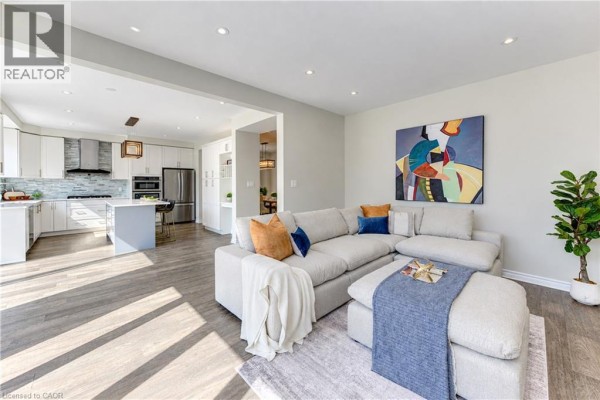Open concept living room with sectional sofa and view into the modern kitchen. - 365 Woolwich Street, Waterloo