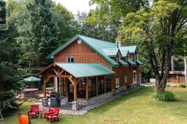 Rear exterior of a wooden house with screened-in porch, hot tub, and outdoor seating area. - 3650 Muskoka Road 117, Lake Of Bays