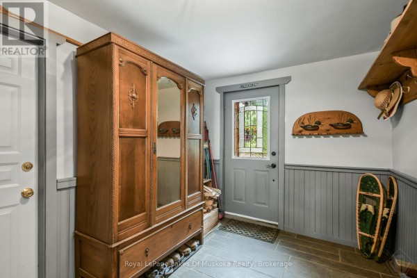 Entrance foyer with a large wooden armoire, stone tile floor, and wall-mounted duck decor. - 3650 Muskoka Road 117, Lake Of Bays