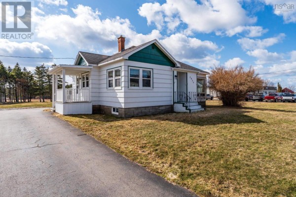 Side view of a white bungalow with a brick chimney, covered porch, and grassy lawn. - 3654 Highway 1, St  Bernard