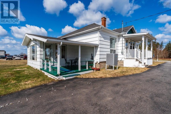 View of the side and back of the white bungalow, featuring a green-covered porch with chairs. - 3654 Highway 1, St  Bernard