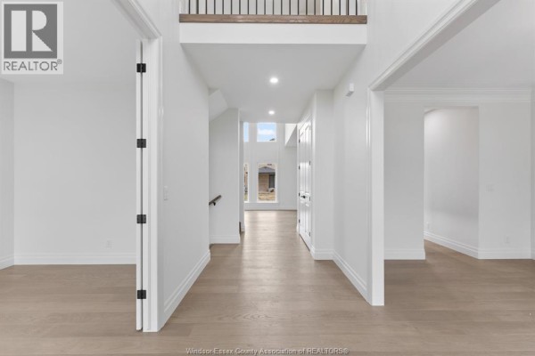 Wide view of the foyer with light hardwood floors, white walls, and stairs leading to the second floor. - 3657 Oakridge Avenue, Windsor