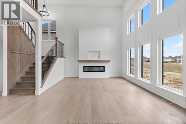 Living room with a modern fireplace, large windows, and a view of the exterior construction site. - 3657 Oakridge Avenue, Windsor