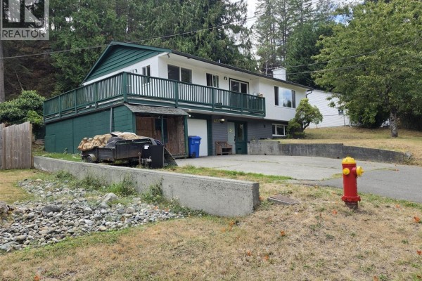 View of the driveway, attached garage, and front entrance of the house with a fire hydrant nearby. - 3657 Sunrise Pl, Nanaimo