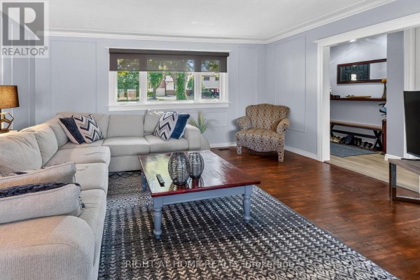Living room with a sectional sofa, armchair, and doorway to the hallway. - 366 Burlington Crescent, London South