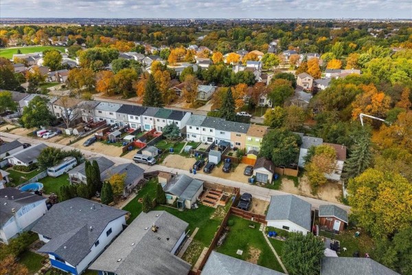 Aerial view of a townhouse complex with backyards and surrounding houses. - 366 Houde Drive, Winnipeg