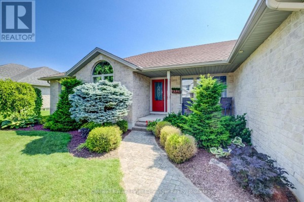 Close-up of the front entrance with a red door, arched window, and landscaped bushes. - 366 Westwood Drive, Brockton