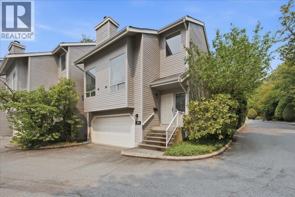 Front exterior of a townhouse featuring gray siding, a white garage door, and an elevated entrance. - 3661 Handel Avenue, Vancouver