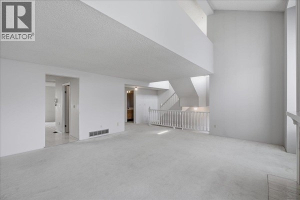 Living area showcasing a staircase and a double-height ceiling with natural light from skylights. - 3661 Handel Avenue, Vancouver