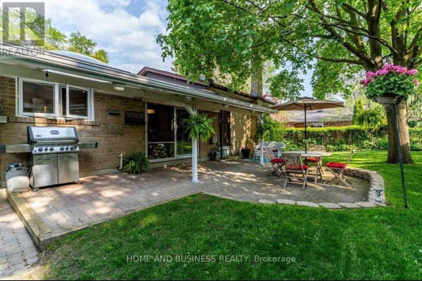 Side view of the backyard patio with a gas grill, patio furniture, and mature trees. - 3668 The Credit Woodlands Road, Mississauga