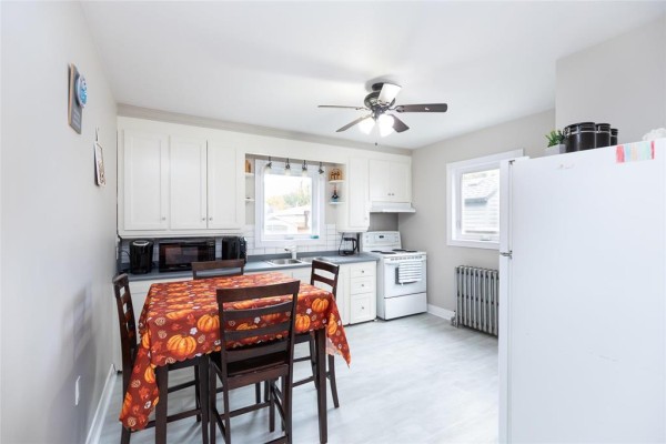 Kitchen with white cabinets, dark countertops, a table set for four, and a white refrigerator. - 367 Jamison Avenue, Winnipeg