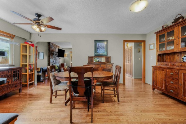 Dining area with a round wooden table, four chairs, and a large wooden hutch. - 3670 207b Street, Langley