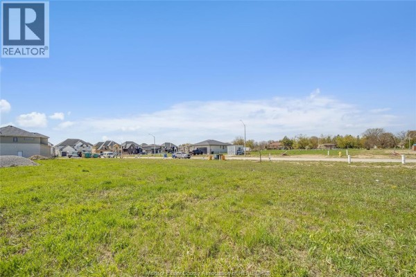 A large empty green lot with new residential construction visible on the horizon. - 3674 Farrow Avenue, Windsor