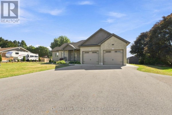 A wide shot of a beige brick bungalow with a grey roof and a two-car garage. - 3677 59 Highway, Norfolk