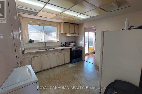 Kitchen with light-colored cabinets, granite countertops, appliances, and a door leading outside. - 3677 Woodruff Crescent, Mississauga
