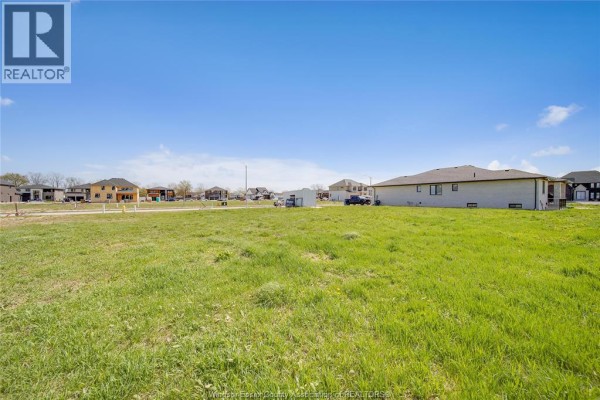 Expansive vacant lot with green grass and houses under construction and completed in the distance. - 3679 Farrow Avenue, Windsor