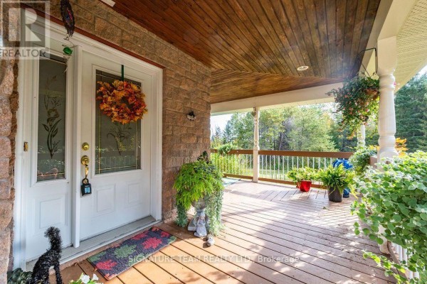 Close-up of a covered front porch with a white door and stone accents. - 368 Dombroskie Road, Whitewater Region