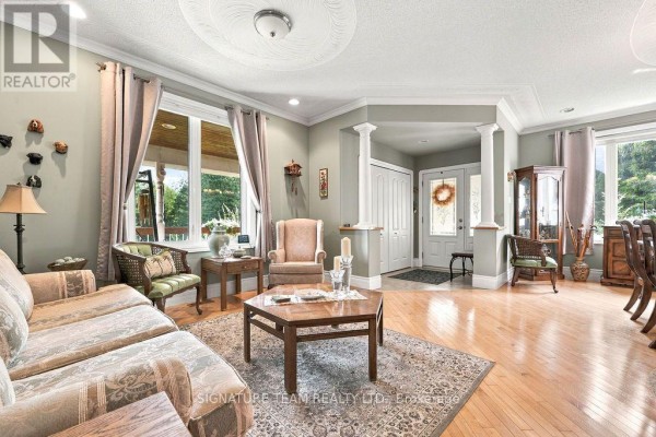 Living room with a patterned sofa, armchair, coffee table, and large windows. - 368 Dombroskie Road, Whitewater Region