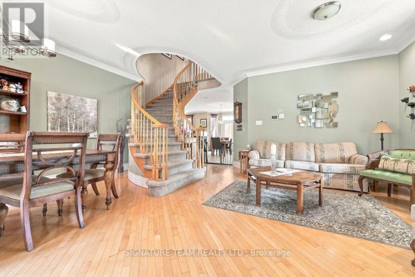 Living and dining room with a curved staircase, hardwood floors, and plush seating. - 368 Dombroskie Road, Whitewater Region