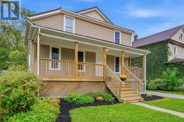 View of the house from the side, highlighting the porch, wooden railings, and beige siding. - 368 Niagara Street, Welland