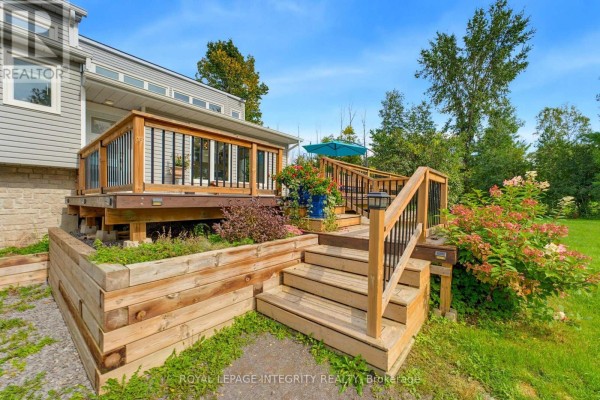 Wooden deck and tiered planters with stairs leading to the house exterior, surrounded by greenery. - 368 Ramsay Concession 5a Road, Mississippi Mills