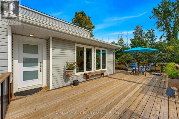 Wooden deck with outdoor furniture, featuring a front door and large windows of the house. - 368 Ramsay Concession 5a Road, Mississippi Mills