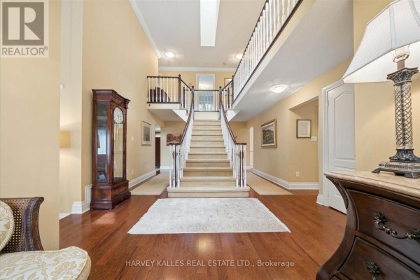 Spacious foyer with hardwood floors, a grand staircase, and a grandfather clock. - 3685 St. Laurent Court, Mississauga