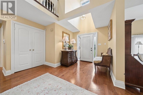 Foyer with cream walls, hardwood floors, double doors, and a wicker bench. - 3685 St. Laurent Court, Mississauga