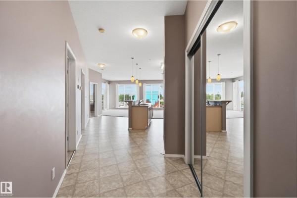 Open-concept living and kitchen area with light wood cabinets, beige carpet, and furniture. - #369 4823 104a St Nw, Edmonton