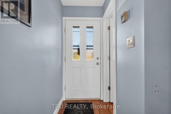Living and dining area with light blue walls, gray sofa, wooden dining set, and hardwood floors. - 369 Mockingbird Drive, Ottawa