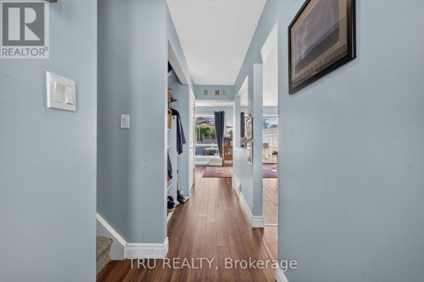Living room area with television on wooden stand, dining table, and light blue walls. - 369 Mockingbird Drive, Ottawa