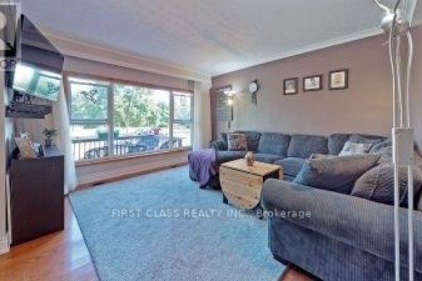 Living room with large sectional sofa, coffee table, blue rug, and wide window. - 369 Paliser Crescent S, Richmond Hill