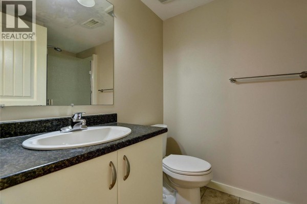 Bathroom with a vanity, toilet, and a mirror reflecting a shower stall. - 369 Wallace Road, Kelowna