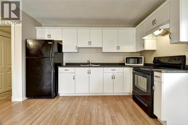 Kitchen with white cabinetry, black appliances including a refrigerator, stove, and microwave. - 369 Wallace Road, Kelowna