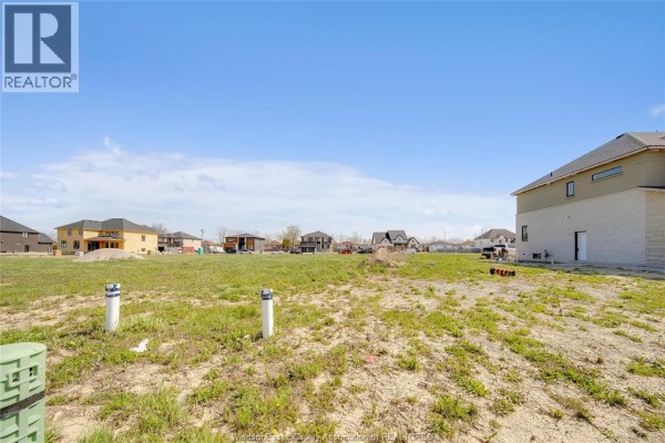 Residential lot with new homes under construction and visible utility posts in the foreground. - 3697 Farrow Avenue, Windsor