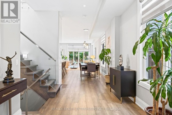Open concept living area with white cabinetry, fireplace, television, and view of kitchen. - 36b Pine Avenue, Mississauga