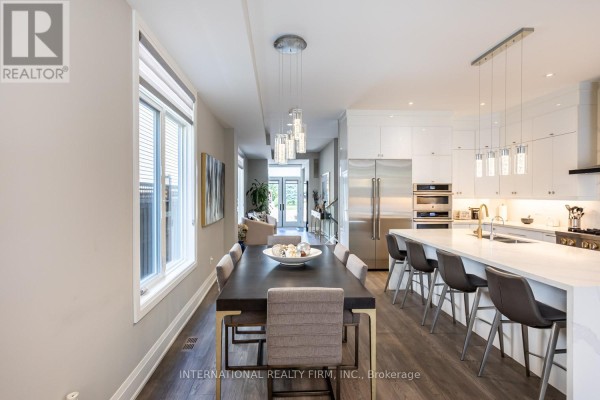 Dining room with dark table and kitchen island with bar stools - 36b Pine Avenue Mississauga