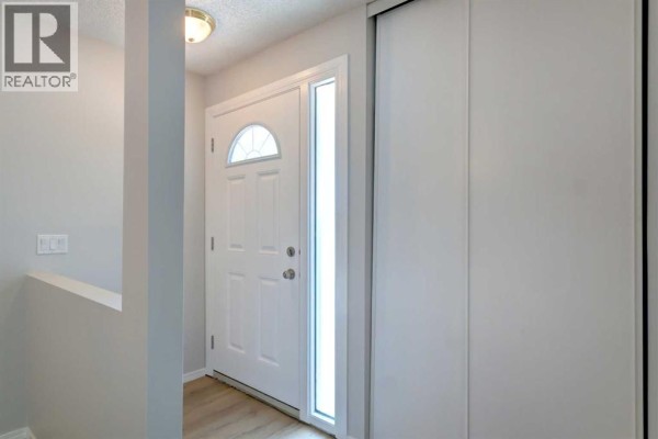 Interior entrance hallway with a white front door, a tall window, and a large white closet. - 37, 3015 51 Street Sw, Calgary