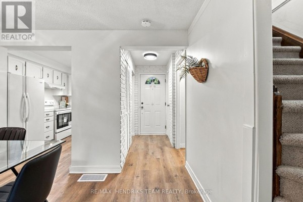 Interior hallway with white walls, wood floors, and staircase. - 37 - 151 Linwell Road, St  Catharines