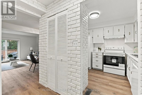 Hallway with white brick partition, louvered doors, and white kitchen. - 37 - 151 Linwell Road, St  Catharines