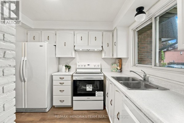 White kitchen with refrigerator, stove, sink, and window. - 37 - 151 Linwell Road, St  Catharines