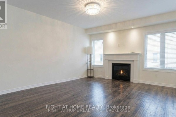 Spacious living room with dark hardwood floors, a white fireplace, and large windows. - 37 - 19 Ridge Road, Cambridge