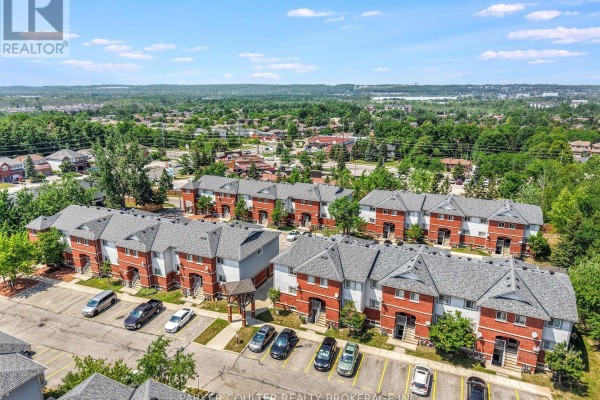 Aerial view of a complex of red brick townhouses with grey roofs under a blue sky. - 37 - 241 Ferndale Drive S, Barrie