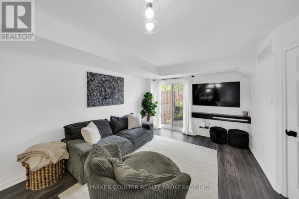Living room with a grey sectional sofa, armchair, television, and white doors. - 37 - 241 Ferndale Drive S, Barrie