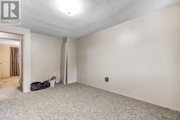 Unfinished room with light grey carpet, cream walls, and a doorway to another room on the left. - 37 - 455 Springbank Avenue N, Woodstock